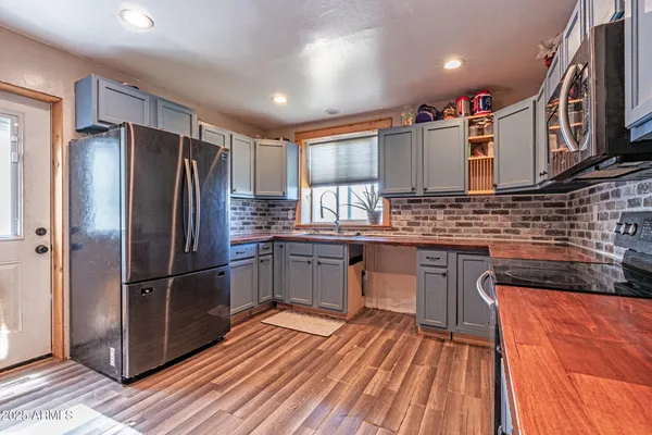 a kitchen with stainless steel appliances granite countertop a refrigerator a sink dishwasher a stove and white countertops with wooden floor