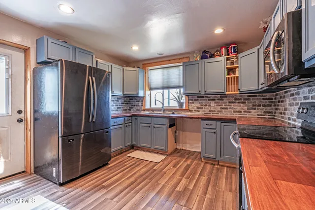 a kitchen with stainless steel appliances granite countertop a refrigerator a sink dishwasher a stove and white countertops with wooden floor