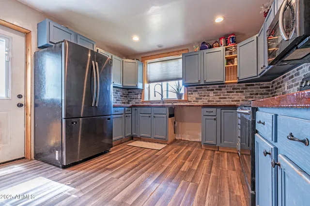 a kitchen with stainless steel appliances granite countertop a refrigerator a stove and a wooden floors