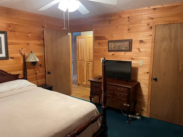 a bedroom with a bed and a flat tv screen on dresser