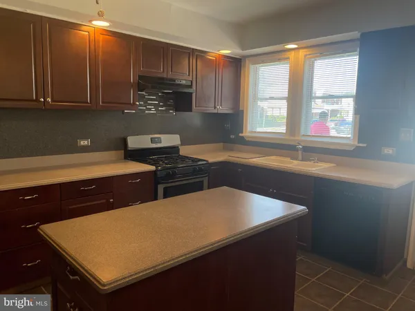 a kitchen with stainless steel appliances a sink dishwasher a stove a refrigerator a sink and dishwasher with wooden cabinets
