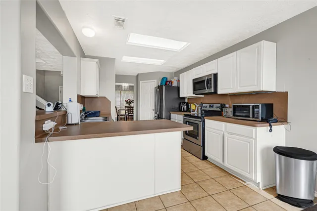 a kitchen with a sink and a stove top oven with white cabinets