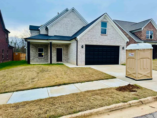 a view of a house with a small yard and large tree