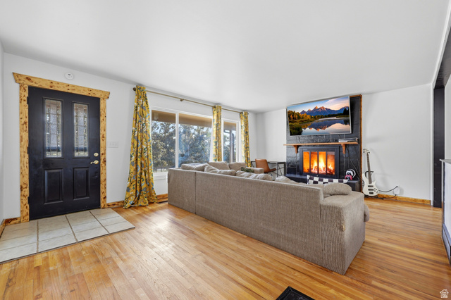 1486 3rd Street Ogden, UT 84404 - Photo 2 of 26 Spacious living area featuring polished wood-finish flooring, a black tiled fireplace with a wood mantle, and a large picture window