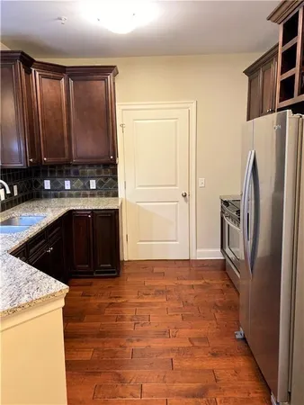 a kitchen with stainless steel appliances granite countertop a refrigerator a stove and a sink with wooden cabinets