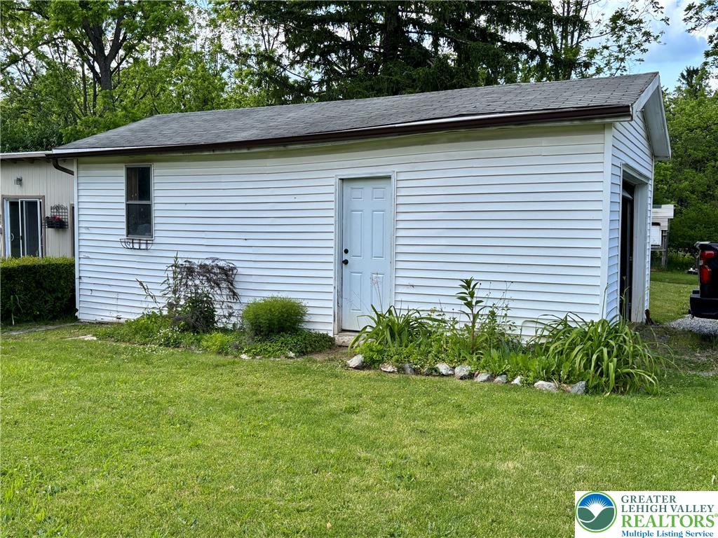 7241 Decatur Street New Tripoli, PA 18066 - Photo 30 of 36 A detached storage building with siding and a well-kept lawn, nestled amidst lush trees.