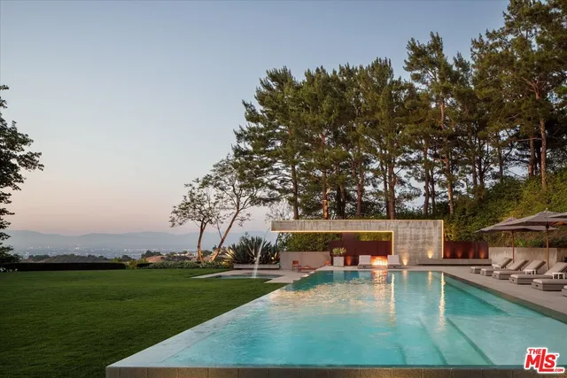 a view of a swimming pool with lawn chairs and a big yard