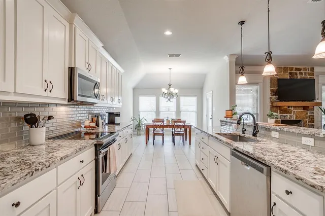 a large kitchen with kitchen island a large counter space a sink appliances and cabinets