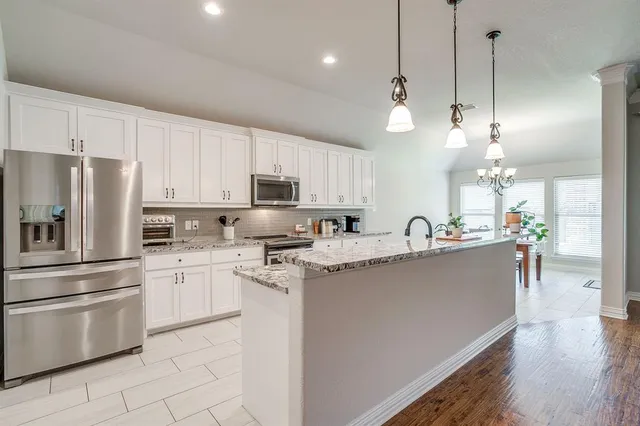 a large kitchen with kitchen island a counter space a sink appliances and a living room view