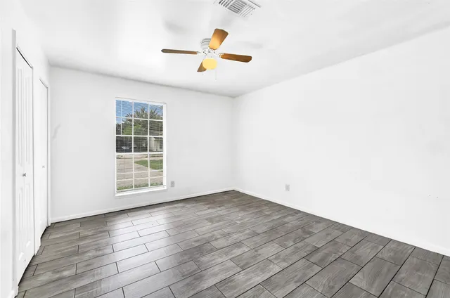 an empty room with wooden floor and windows