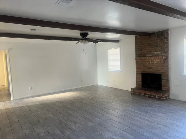 an empty room with wooden floor a fireplace and windows