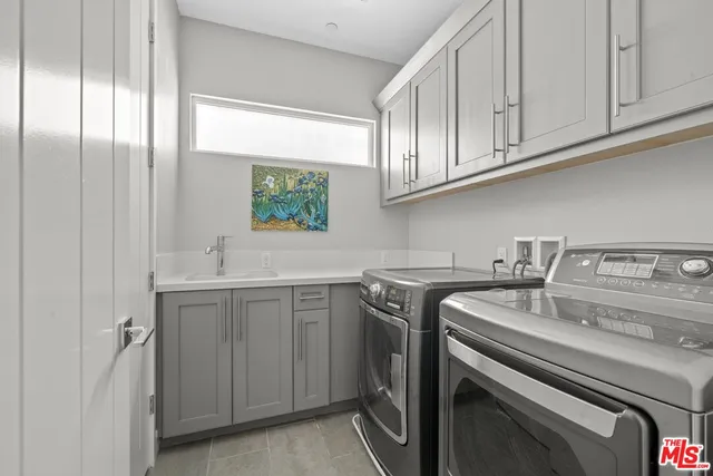 a utility room with stainless steel appliances granite countertop a sink dishwasher a washer and dryer with cabinets