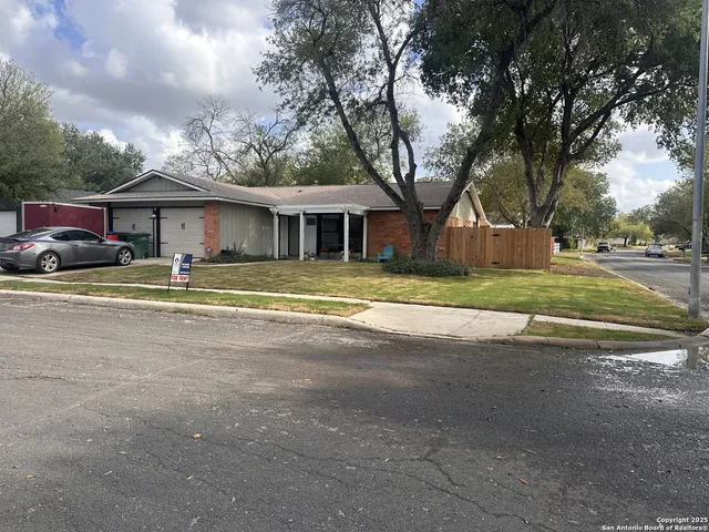 a view of a house with a yard and large trees