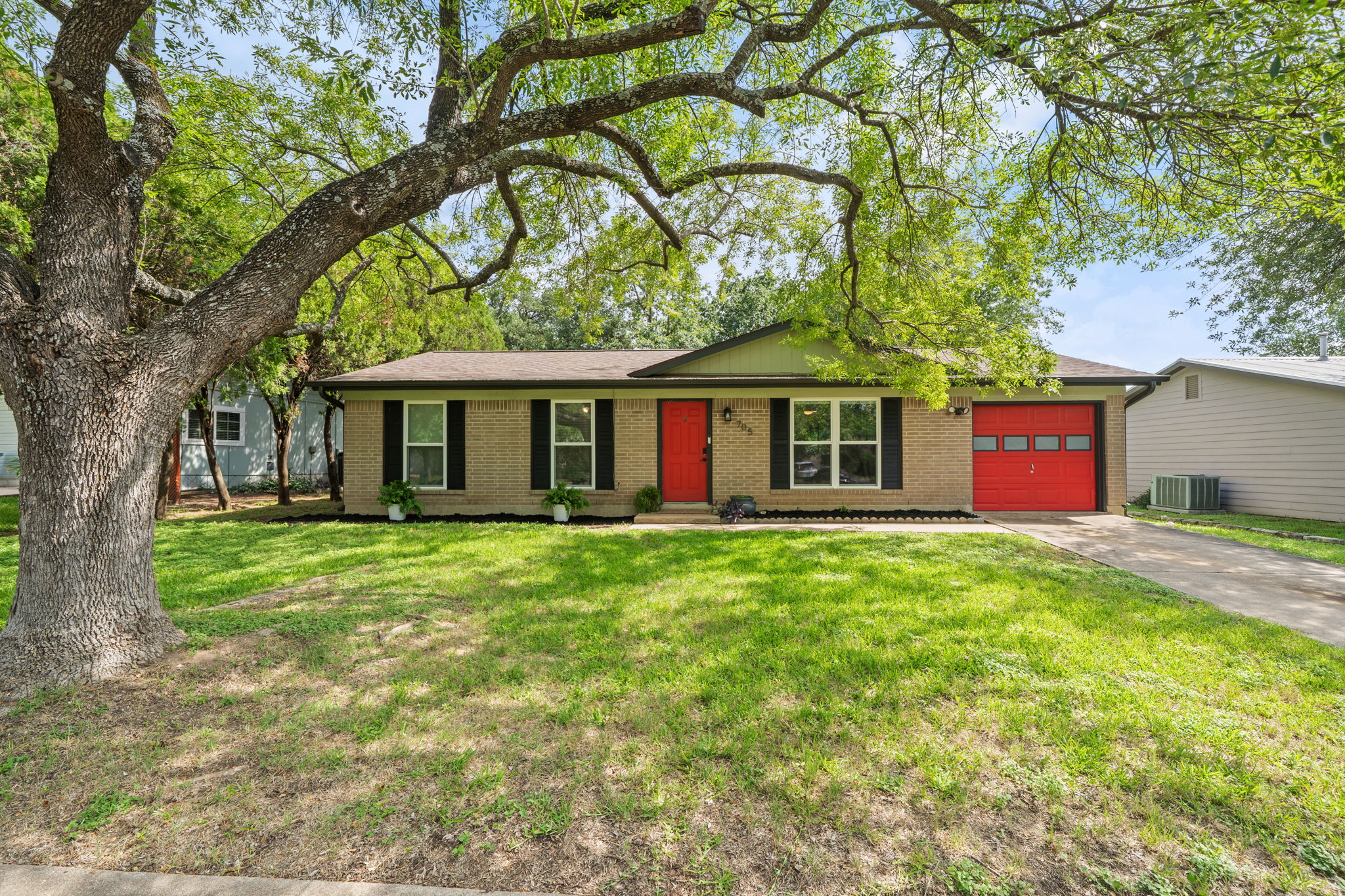 705 Dulwich Street Austin, TX 78748 - Photo 36 of 36 A charming single-story residence boasts a vibrant red entry door and garage door, complemented by a welcoming green lawn.