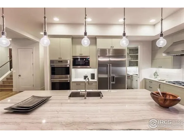 a kitchen with stainless steel appliances kitchen island granite countertop a stove a refrigerator a sink and a dining table with wooden floor