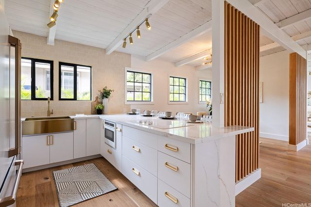 a large white kitchen with a window and stainless steel appliances