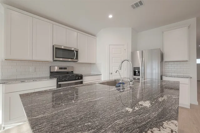 a kitchen with granite countertop a stove a sink a microwave and refrigerator