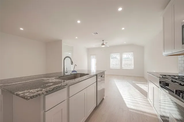 a kitchen with granite countertop a sink stove and cabinets
