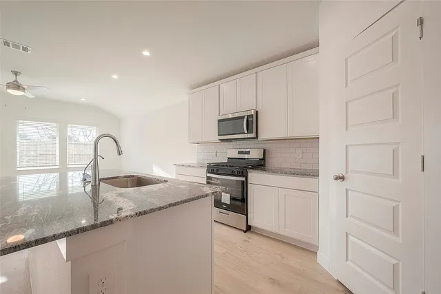 a kitchen with granite countertop white cabinets and appliances