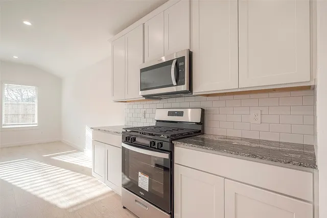 a kitchen with stainless steel appliances granite countertop white cabinets granite counter tops and a wooden floors