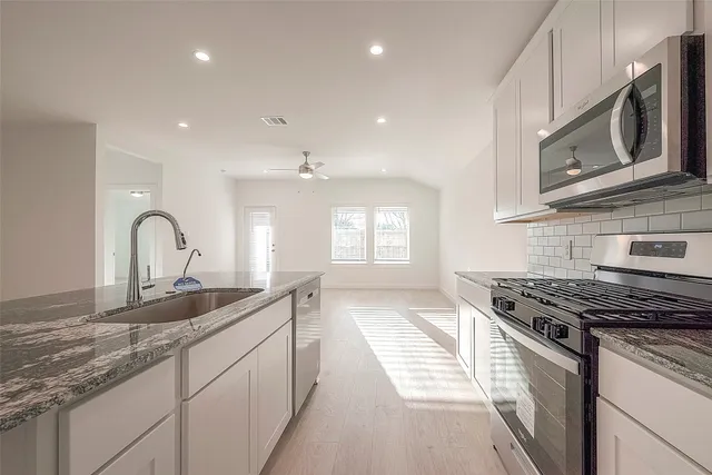 a kitchen with stainless steel appliances granite countertop a sink stove and cabinets