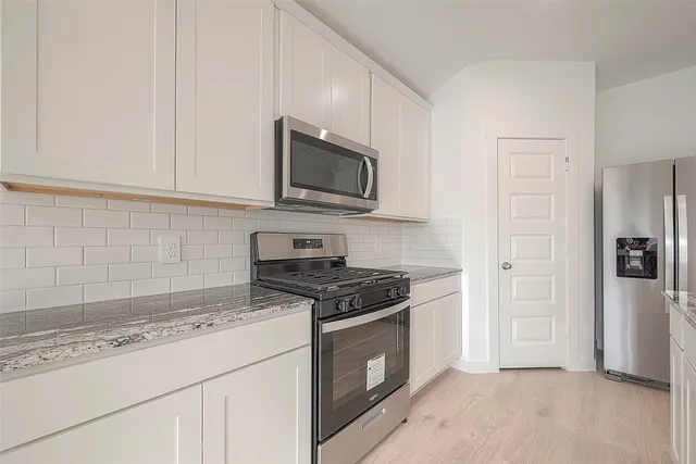 a kitchen with granite countertop white cabinets and stainless steel appliances