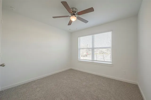an empty room with a window and a ceiling fan