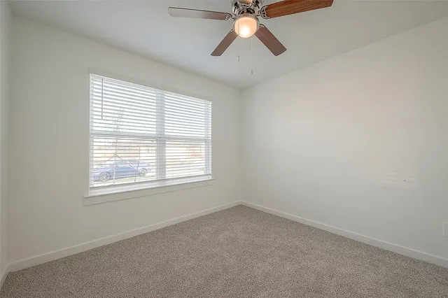 an empty room with a window and a fan
