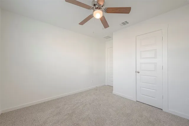 an empty room with closet and a chandelier fan