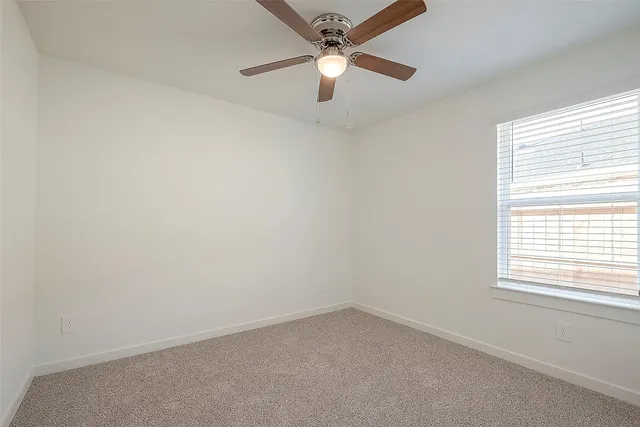 an empty room with a window and a fan