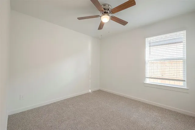 an empty room with a window and a fan