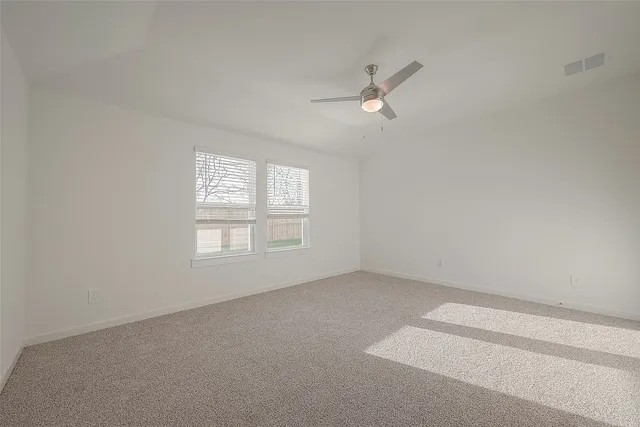 an empty room with a window and ceiling fan