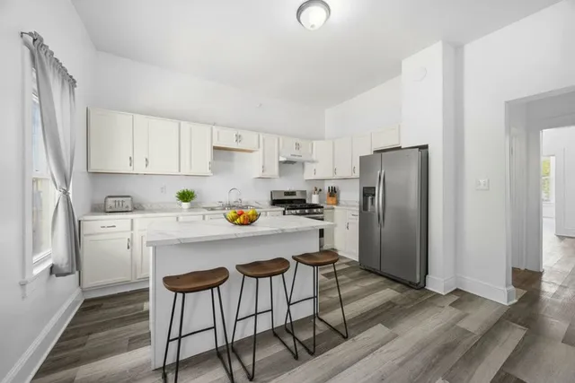 a kitchen with stainless steel appliances a refrigerator a stove a sink and white cabinets with wooden floor