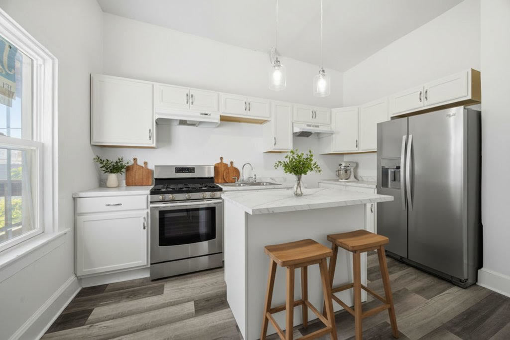 8919 South Exchange Avenue Chicago, IL 60617 - Photo 13 of 41 a kitchen with stainless steel appliances a refrigerator a stove a sink and white cabinets with wooden floor