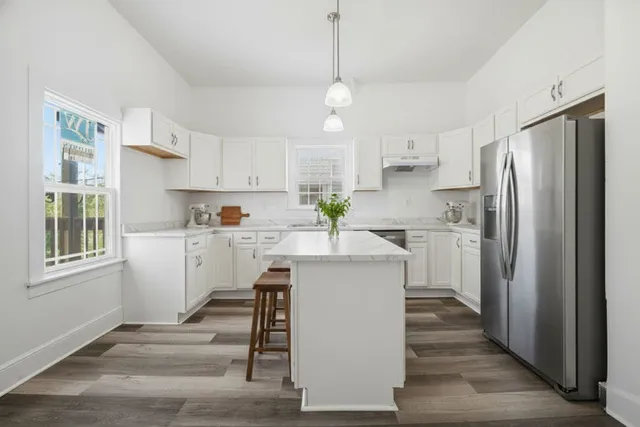 a kitchen with kitchen island white cabinets and stainless steel appliances