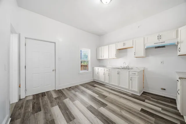 a view of a kitchen with white cabinets and wooden floor