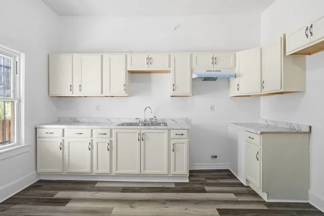 a kitchen with white cabinets and sink
