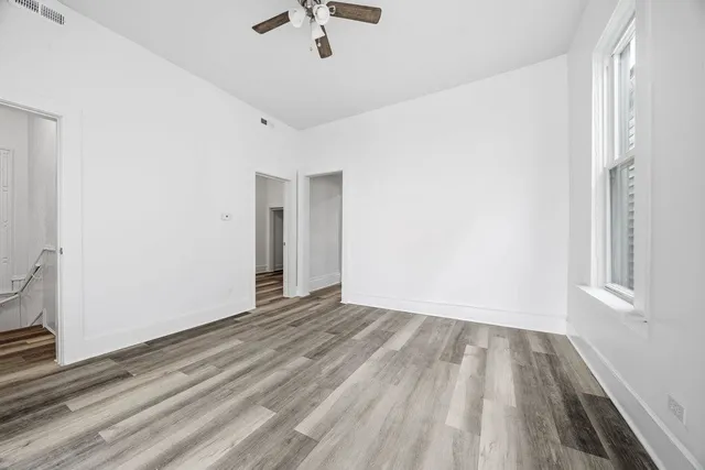 a view of empty room with wooden floor and fan