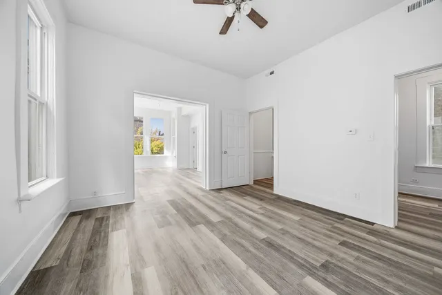 a view of an empty room with wooden floor and a window