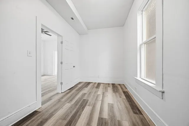 a view of empty room with wooden floor and fan
