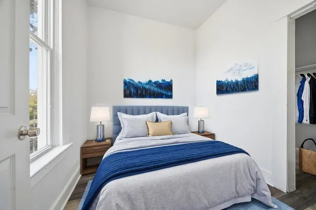 a bedroom with a bed a painting on the wall and a window