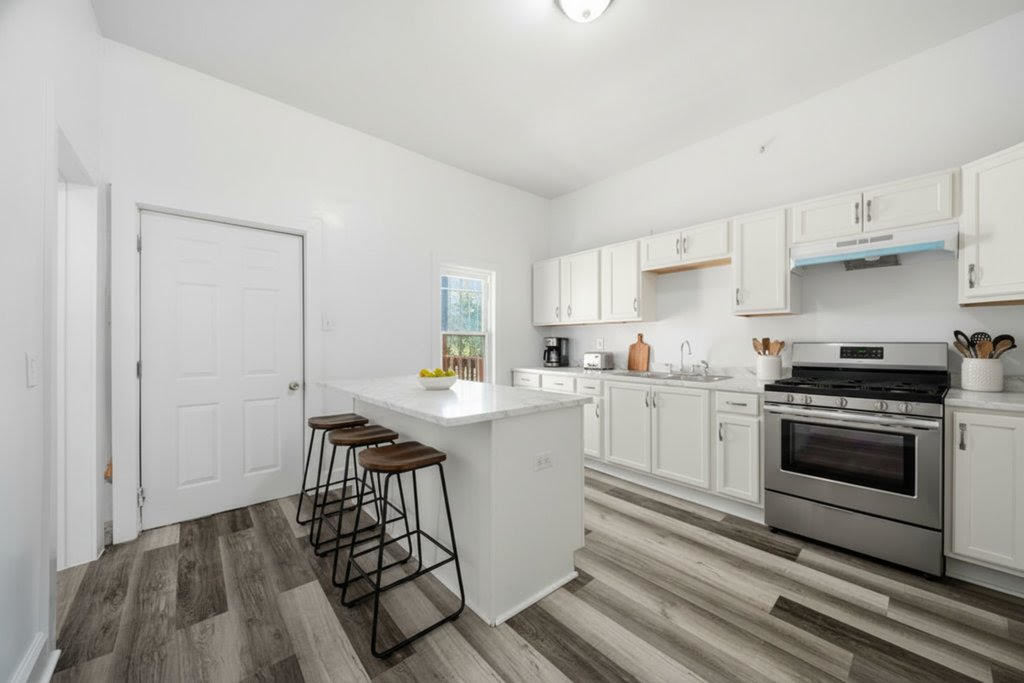 8919 South Exchange Avenue Chicago, IL 60617 - Photo 10 of 41 a kitchen with a sink cabinets stainless steel appliances and a window
