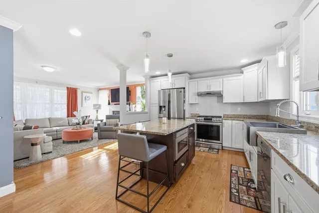 a kitchen with a refrigerator a stove top oven a sink dishwasher and white cabinets with wooden floor