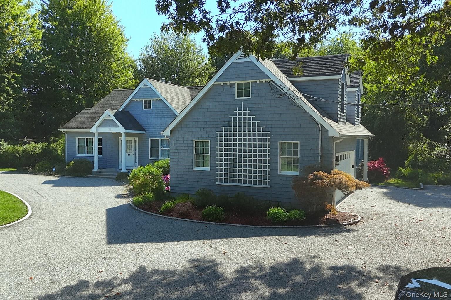 View of front of property featuring driveway, a garage, and roof with shingles