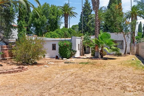 a view of a house with palm trees and a small yard