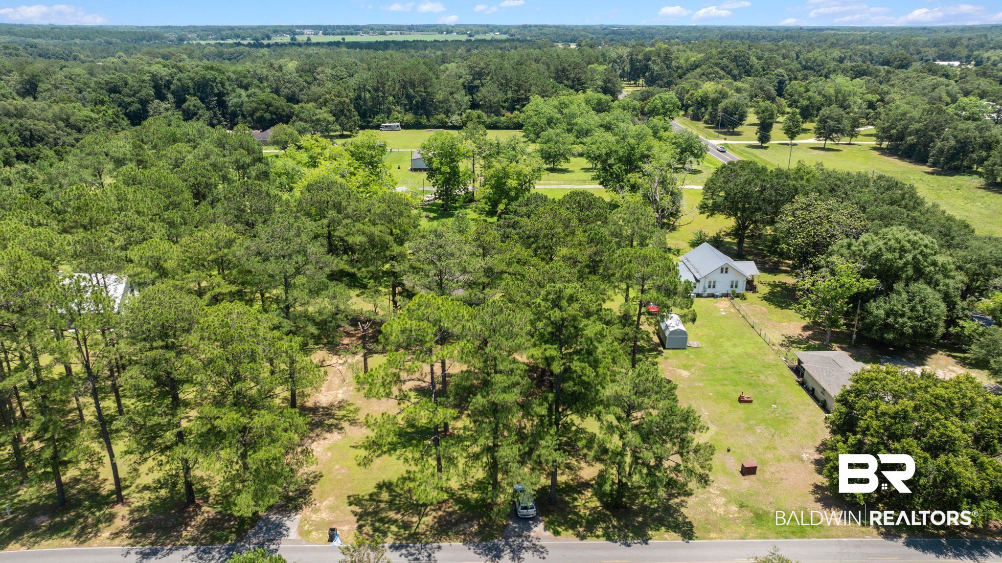 20540 Lacey Road Silverhill, AL 36576 - Photo 30 of 40 Expansive property with a white-sided residence featuring a gray roof, surrounded by mature trees