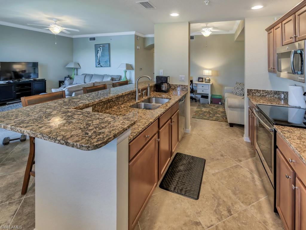 9727 Acqua Court, Unit 427 Naples, FL 34113 - Photo 25 of 29 a large kitchen with kitchen island a sink stove and cabinets