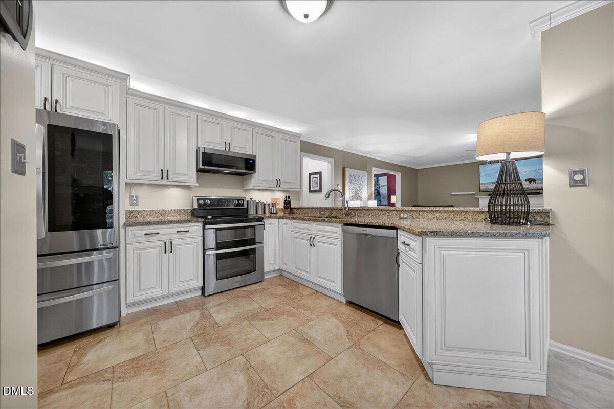 9536 Bells Valley Drive Raleigh, NC 27617 - Photo 13 of 39 a kitchen with granite countertop a refrigerator and a stove top oven