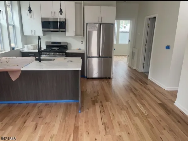 a kitchen with stainless steel appliances a refrigerator sink and wooden floor