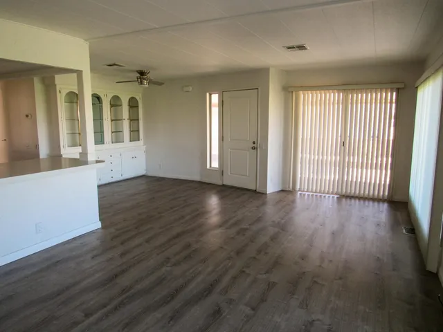 an empty room with wooden floor and windows